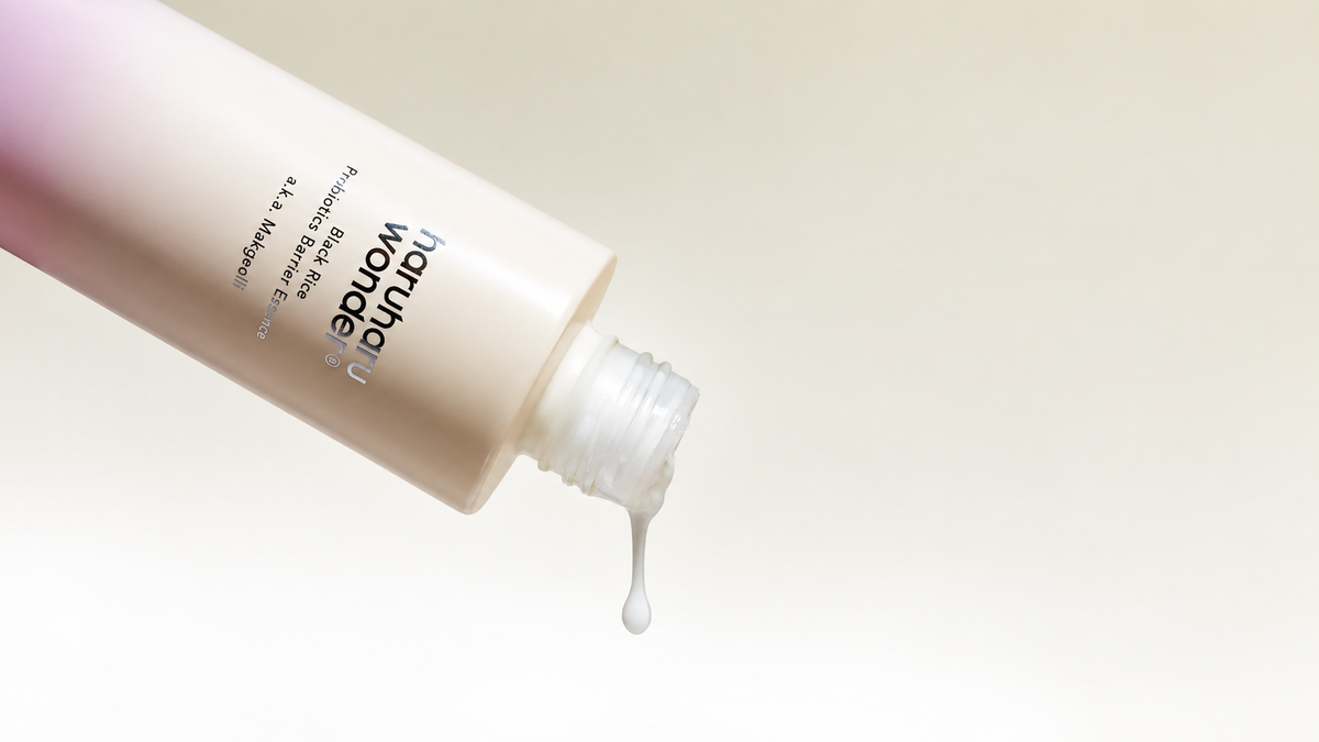 Open HARUHARU WONDER Black Rice Probiotics Barrier Essence bottle dispensing a milky drop against a warm ivory background.
