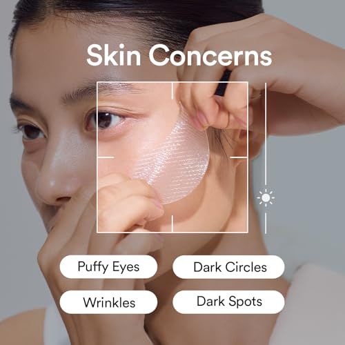 Woman gently patting peptide eye cream beneath one eye beside Korean eye creams and hydrogel eye patches on a sunlit vanity.