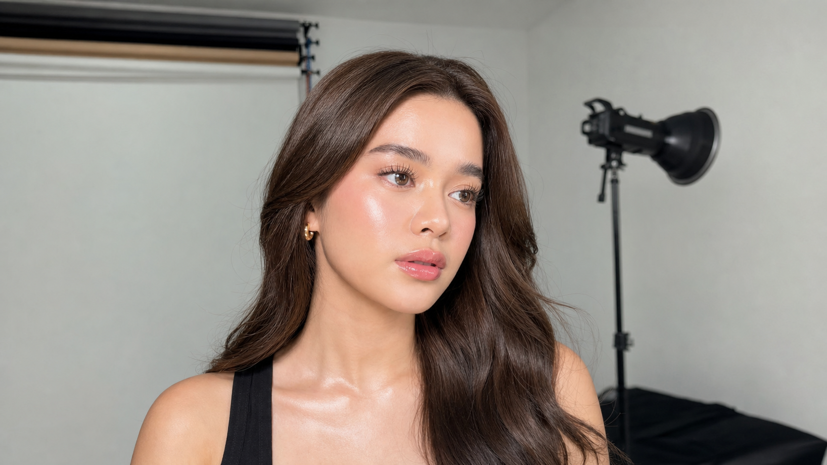 Woman with softly highlighted under-eyes and natural pink makeup in a wide studio portrait for an Aegyo-Sal beginner guide.